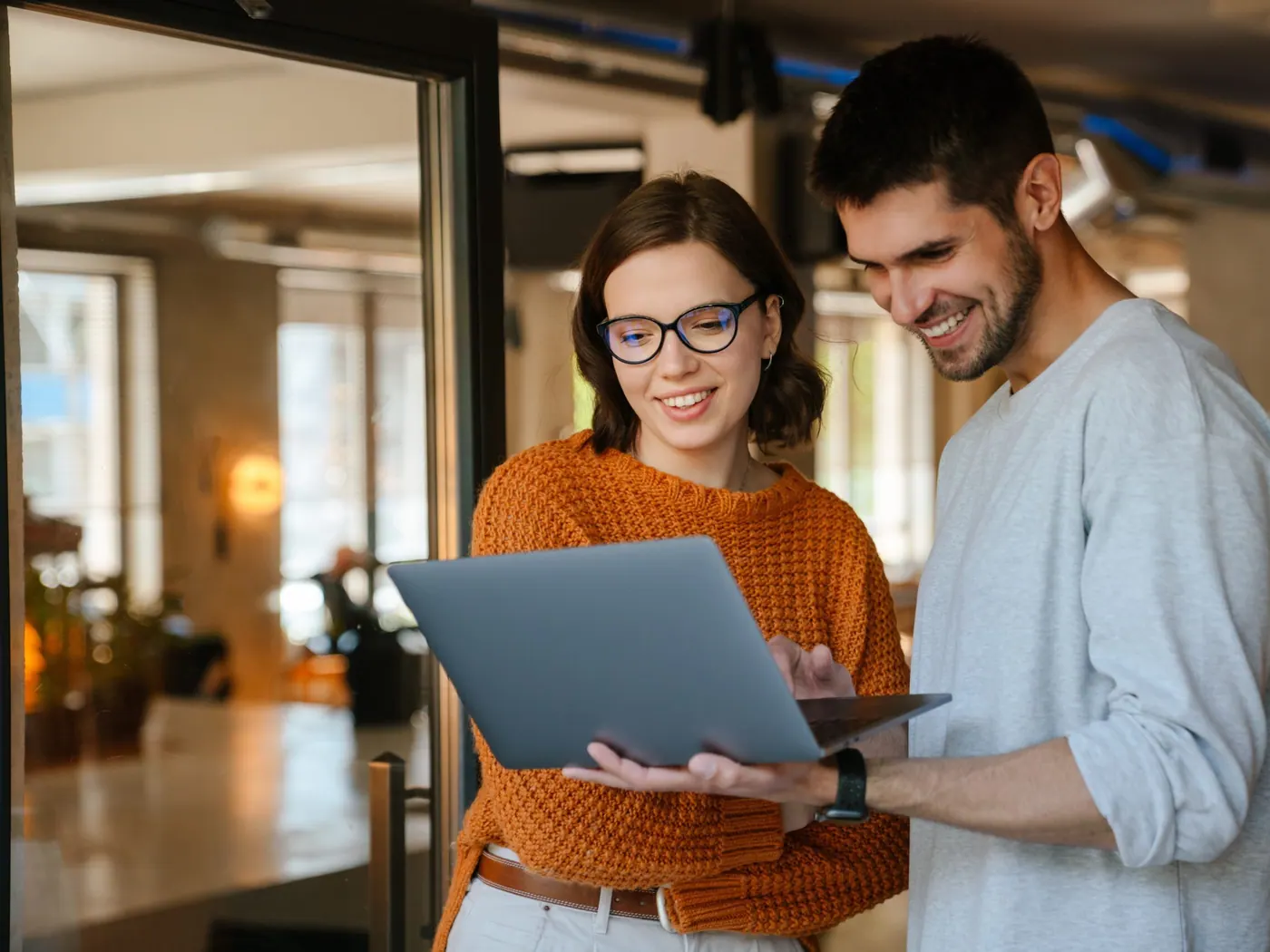 Two colleagues smiling while looking at a laptop